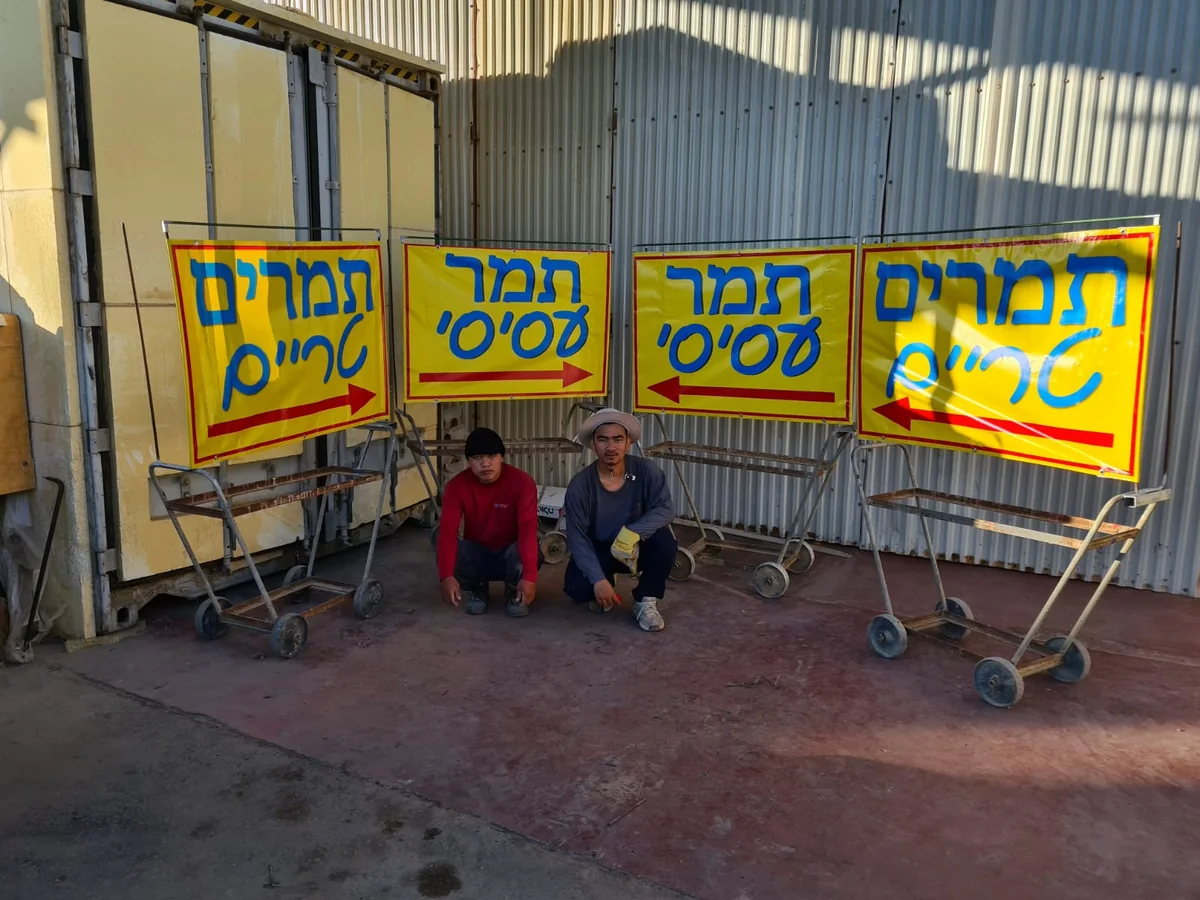 ילדים יושבים לצד שלטים צבעוניים של תמרים לחים