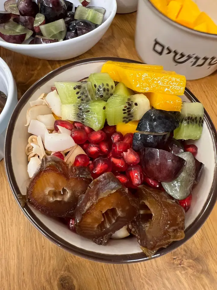 תמרים מגולענים בקערה עם מנגו, קיווי, רימון וקוקוס