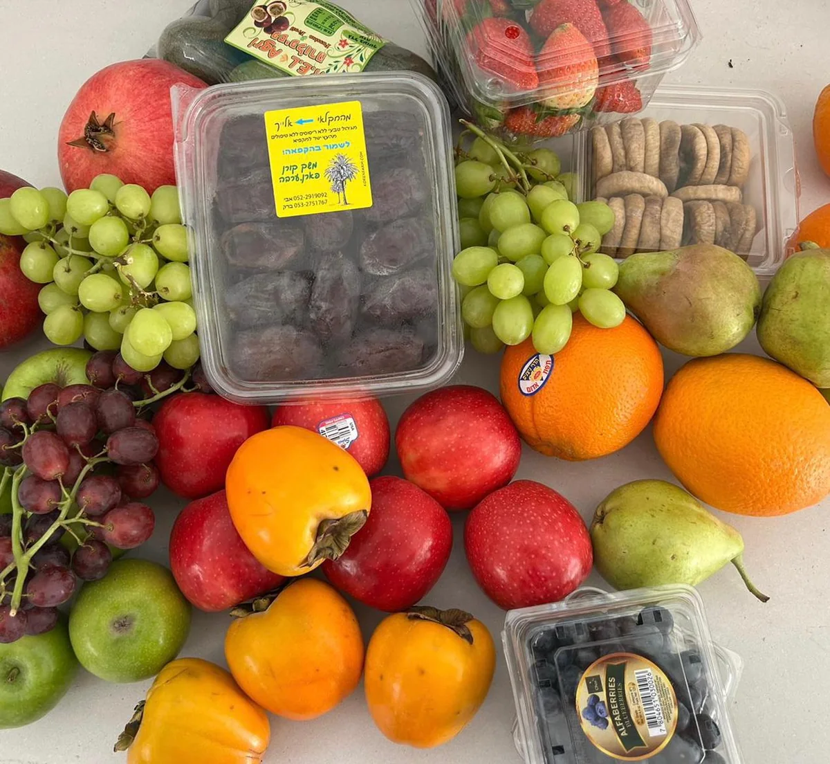 קופסת תמרים בין ענבים, תפוזים, תפוחים ופירות נוספים